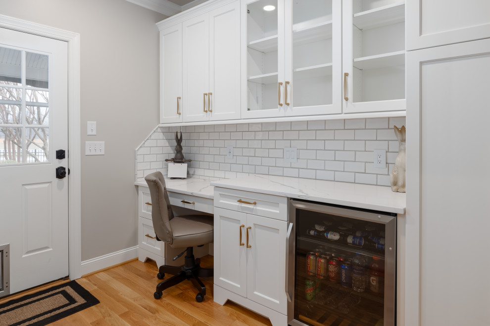 Example of a large transitional u-shaped medium tone wood floor and brown floor eat-in kitchen design in Other with an undermount sink, recessed-panel cabinets, white cabinets, quartz countertops, white backsplash, ceramic backsplash, stainless steel appliances, an island and white countertops