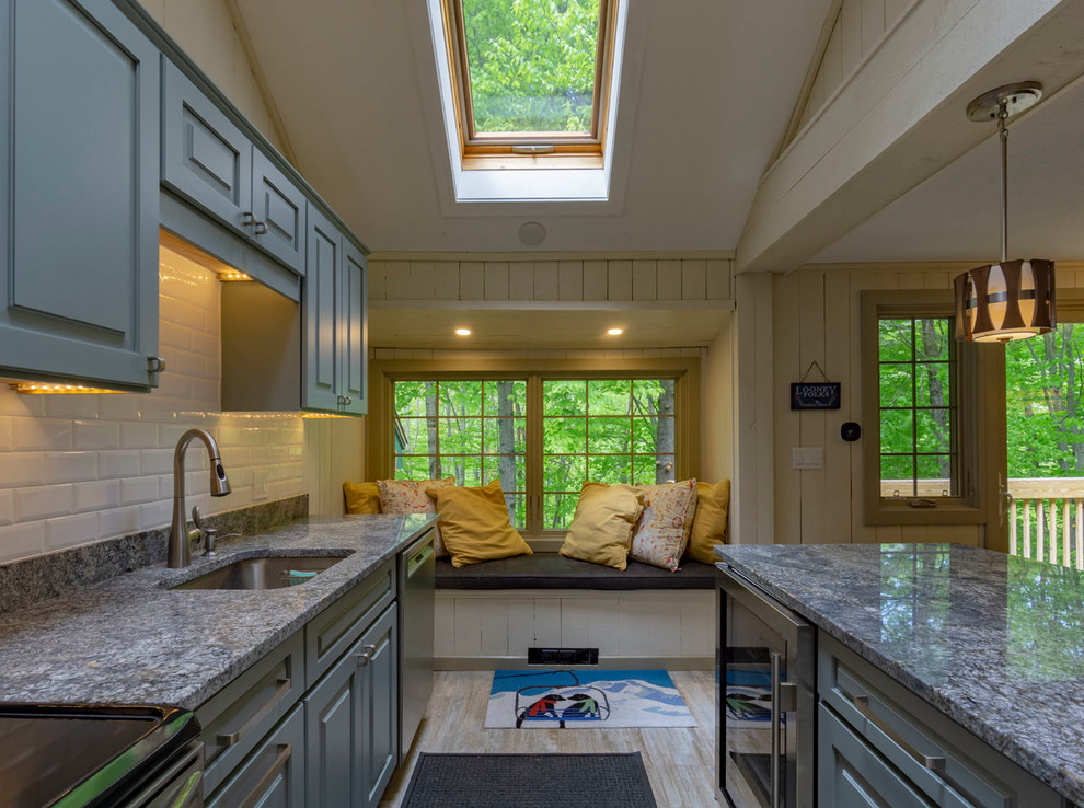 Immagine di un cucina con isola centrale rustico con lavello sottopiano, ante con bugna sagomata, top in granito, paraspruzzi bianco e pavimento in gres porcellanato