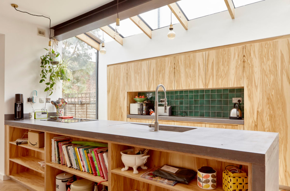 Пример оригинального дизайна: параллельная кухня в современном стиле с монолитной мойкой, плоскими фасадами, фасадами цвета дерева среднего тона, зеленым фартуком, полуостровом и серой столешницей