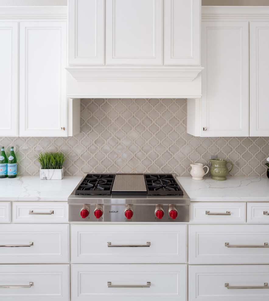 Inspiration for a mid-sized timeless l-shaped porcelain tile and white floor eat-in kitchen remodel in Dallas with an undermount sink, shaker cabinets, white cabinets, quartz countertops, gray backsplash, porcelain backsplash, stainless steel appliances, an island and white countertops