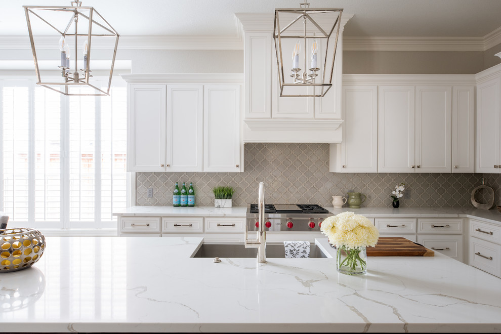 Eat-in kitchen - mid-sized traditional l-shaped porcelain tile and white floor eat-in kitchen idea in Dallas with an undermount sink, shaker cabinets, white cabinets, quartz countertops, gray backsplash, porcelain backsplash, stainless steel appliances, an island and white countertops