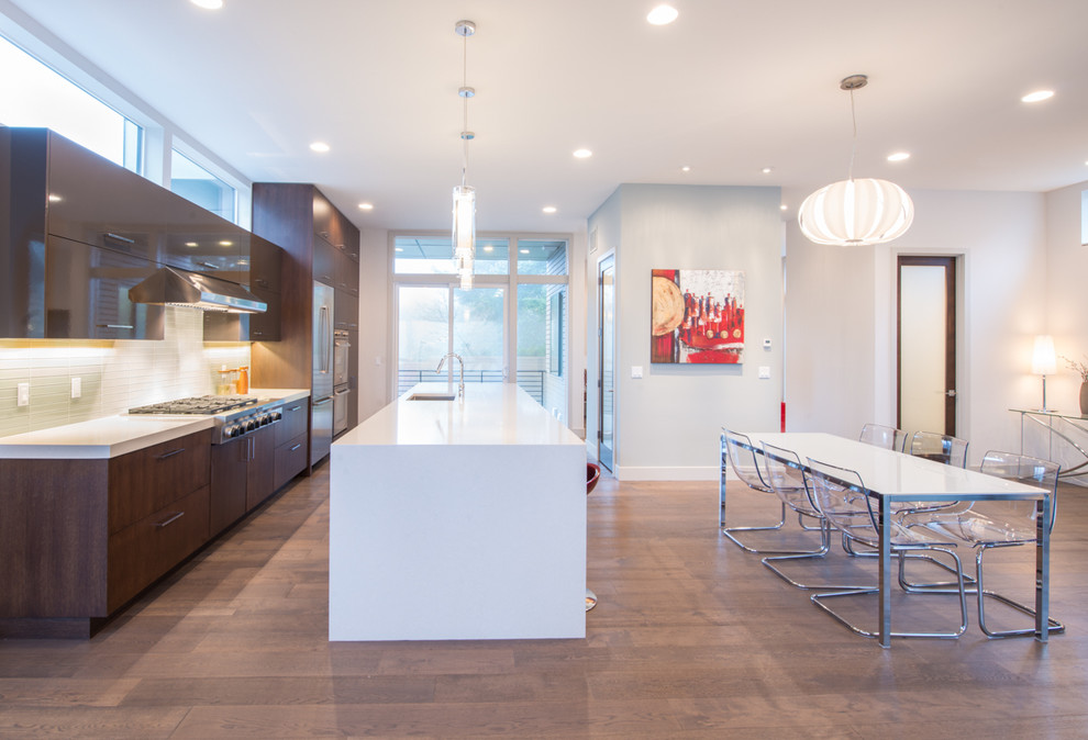 Zweizeilige, Mittelgroße Moderne Wohnküche mit flächenbündigen Schrankfronten, dunklen Holzschränken, Küchengeräten aus Edelstahl, Kücheninsel, Unterbauwaschbecken, Quarzwerkstein-Arbeitsplatte, Küchenrückwand in Weiß, Rückwand aus Glasfliesen und braunem Holzboden in Seattle