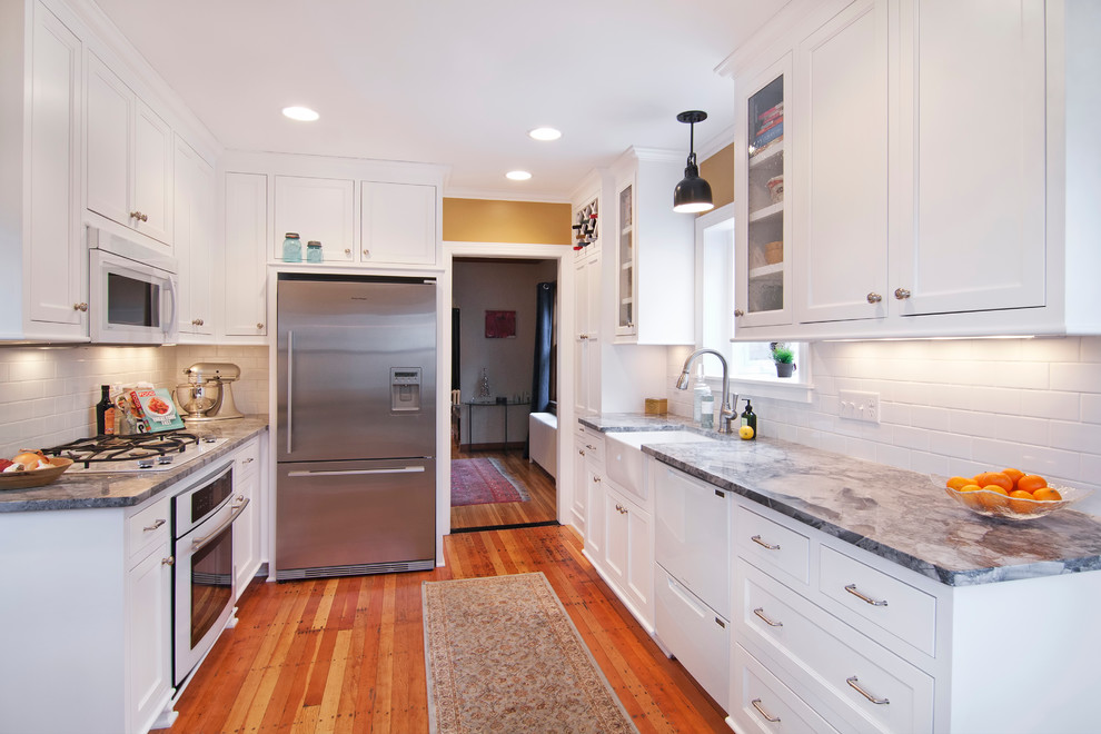 Photo of a traditional kitchen in Minneapolis with stainless steel appliances, a belfast sink, shaker cabinets, white cabinets, white splashback and metro tiled splashback.