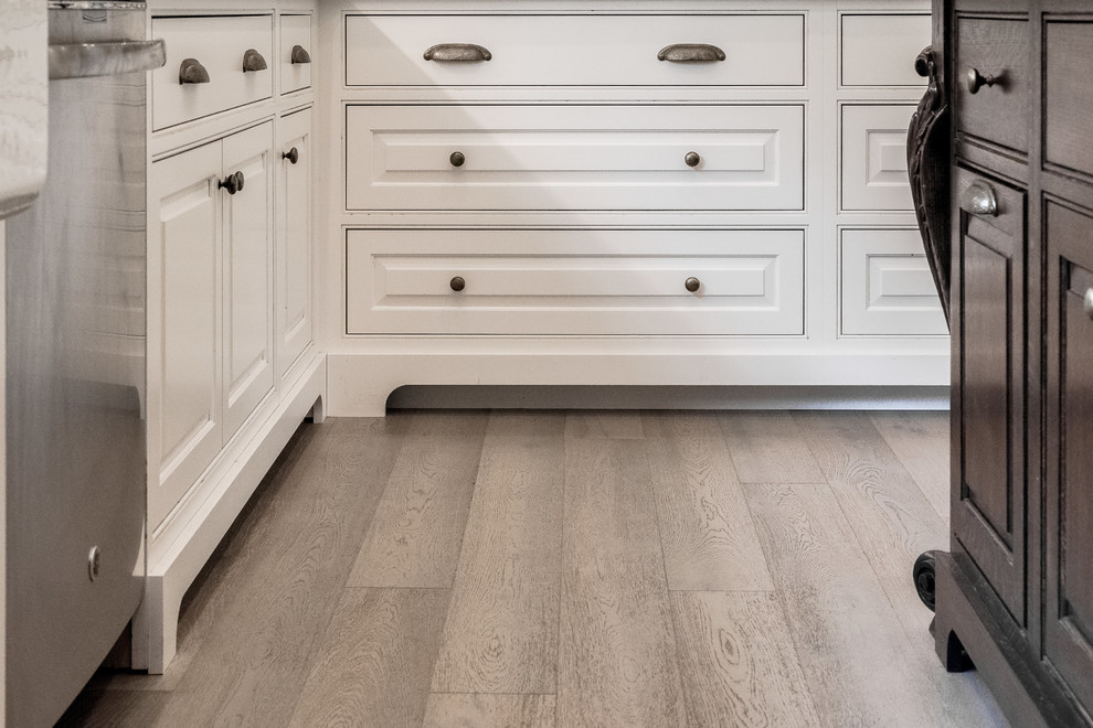 Inspiration for a large timeless u-shaped light wood floor and gray floor eat-in kitchen remodel in Indianapolis with a farmhouse sink, raised-panel cabinets, white cabinets, marble countertops, ceramic backsplash, stainless steel appliances and an island