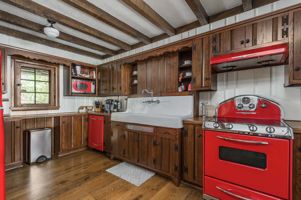 Klassische Küche in L-Form mit Landhausspüle, dunklen Holzschränken, Arbeitsplatte aus Holz, Küchenrückwand in Weiß, bunten Elektrogeräten und dunklem Holzboden in Indianapolis
