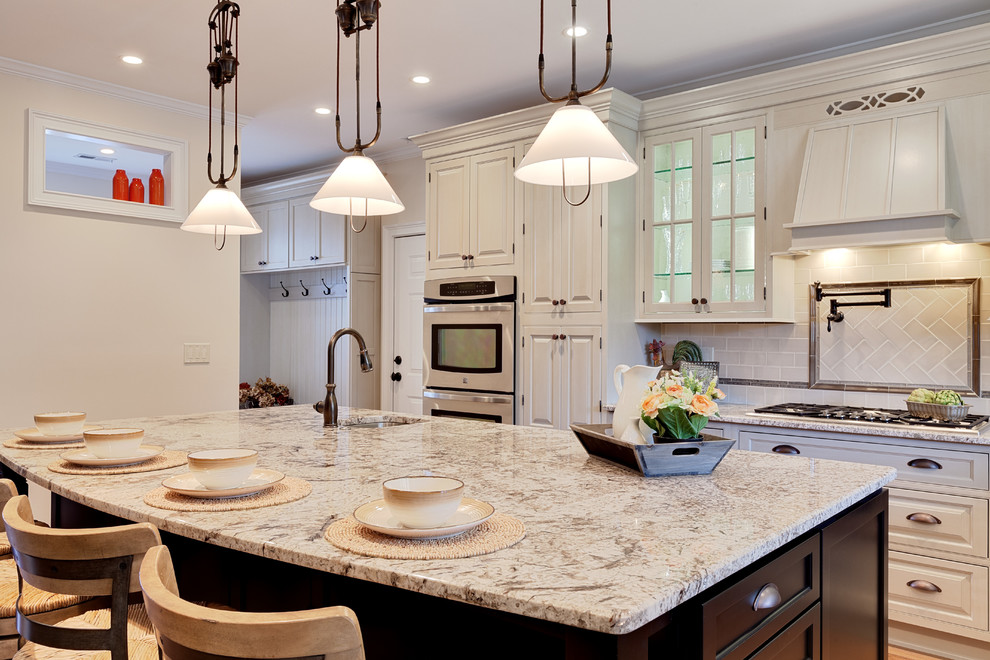 Inspiration for a huge timeless l-shaped medium tone wood floor and brown floor eat-in kitchen remodel in Atlanta with a farmhouse sink, beige cabinets, granite countertops, beige backsplash, porcelain backsplash, stainless steel appliances, an island and beige countertops