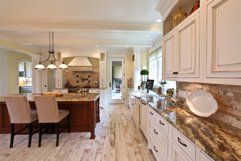 Inspiration for a large timeless l-shaped light wood floor eat-in kitchen remodel in Grand Rapids with a farmhouse sink, recessed-panel cabinets, distressed cabinets, granite countertops, paneled appliances, an island, gray backsplash, stone tile backsplash and beige countertops