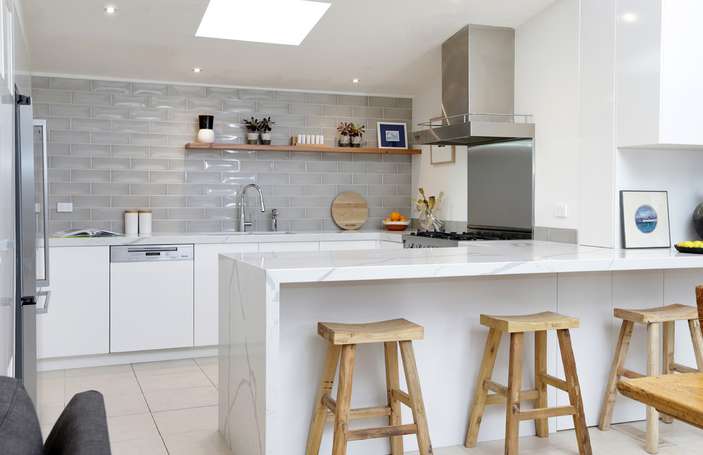 Exempel på ett modernt kök, med släta luckor, vita skåp, marmorbänkskiva, grått stänkskydd, stänkskydd i keramik, vita vitvaror och en halv köksö