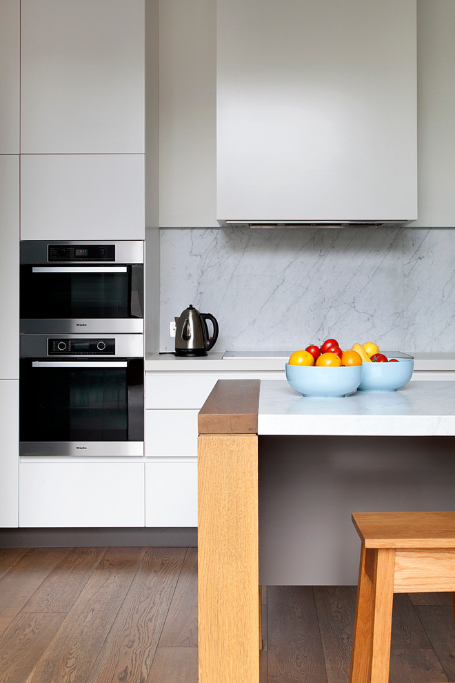 Einzeilige, Mittelgroße Moderne Wohnküche mit Doppelwaschbecken, weißen Schränken, Küchenrückwand in Weiß, Rückwand aus Stein, Küchengeräten aus Edelstahl, dunklem Holzboden und Kücheninsel in Melbourne