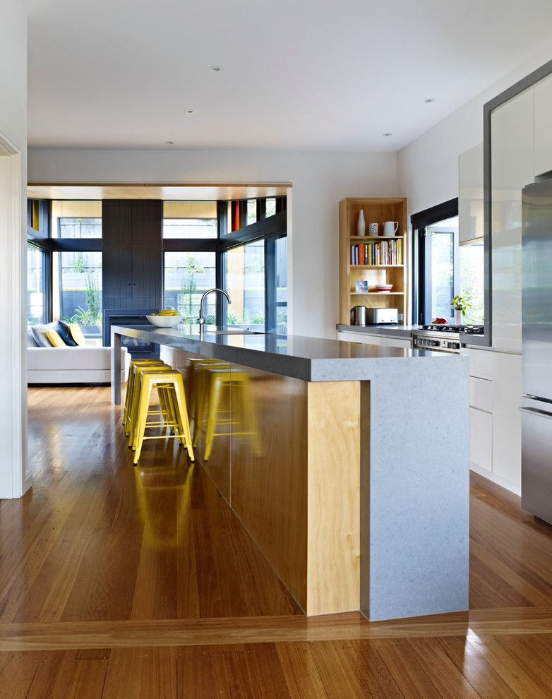 Zweizeilige, Große Moderne Wohnküche mit Unterbauwaschbecken, flächenbündigen Schrankfronten, weißen Schränken, Quarzwerkstein-Arbeitsplatte, Küchengeräten aus Edelstahl, braunem Holzboden und Kücheninsel in Melbourne