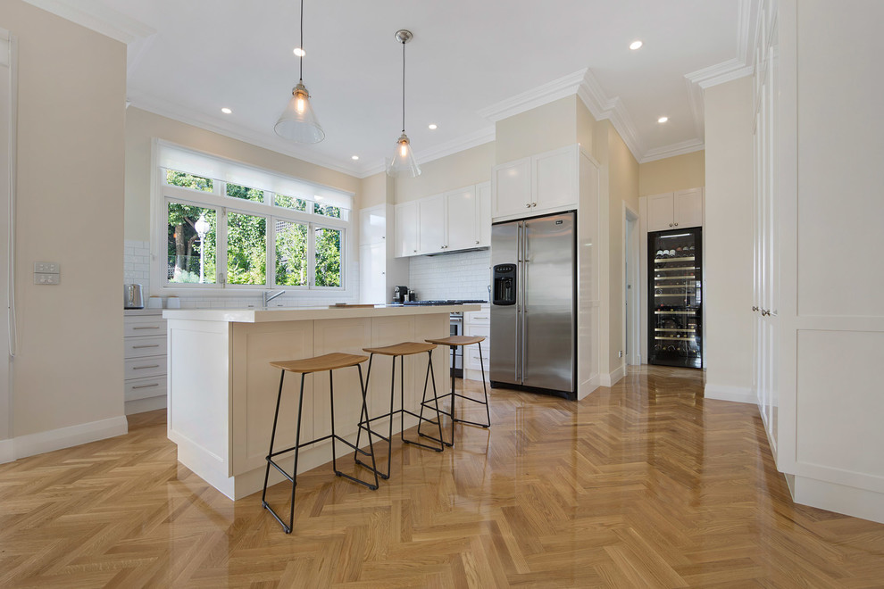Mittelgroße Skandinavische Wohnküche mit weißen Schränken, Rückwand aus Metrofliesen, Küchengeräten aus Edelstahl, hellem Holzboden und Kücheninsel in Melbourne