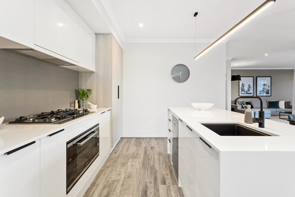 Zweizeilige Moderne Küche mit Unterbauwaschbecken, flächenbündigen Schrankfronten, weißen Schränken, Küchenrückwand in Grau, schwarzen Elektrogeräten, braunem Holzboden, Kücheninsel und grauem Boden in Perth