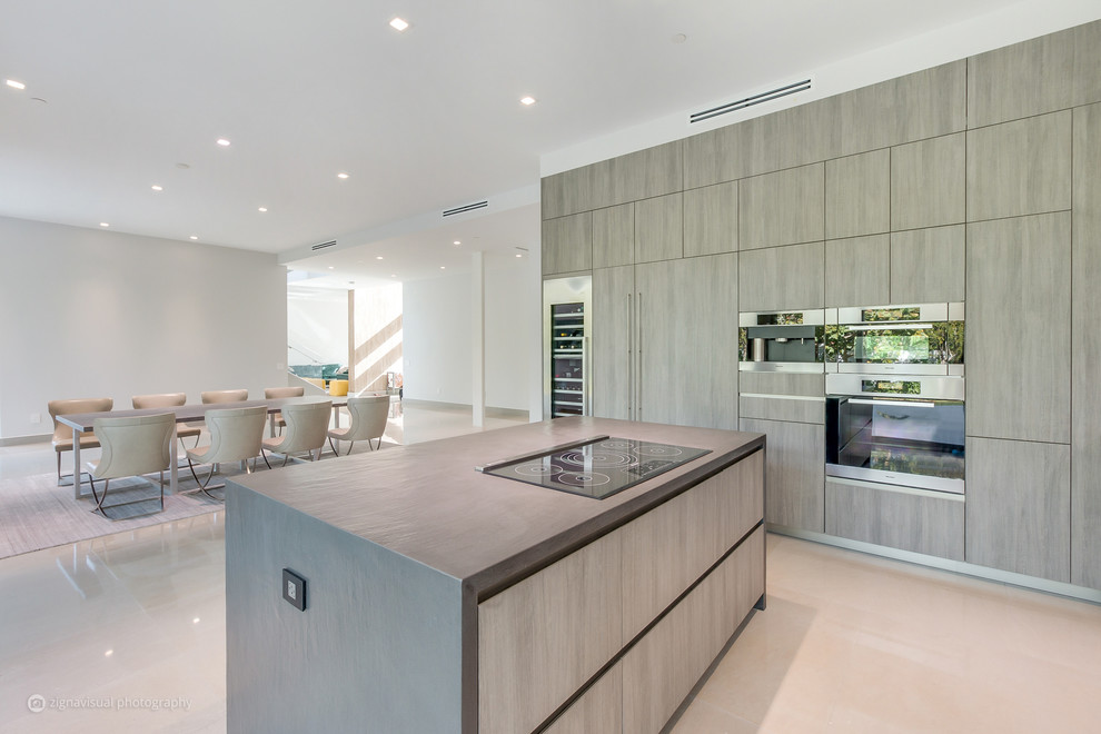 Large minimalist l-shaped marble floor and gray floor kitchen photo in Miami with a drop-in sink, limestone countertops, black backsplash, limestone backsplash, stainless steel appliances and an island