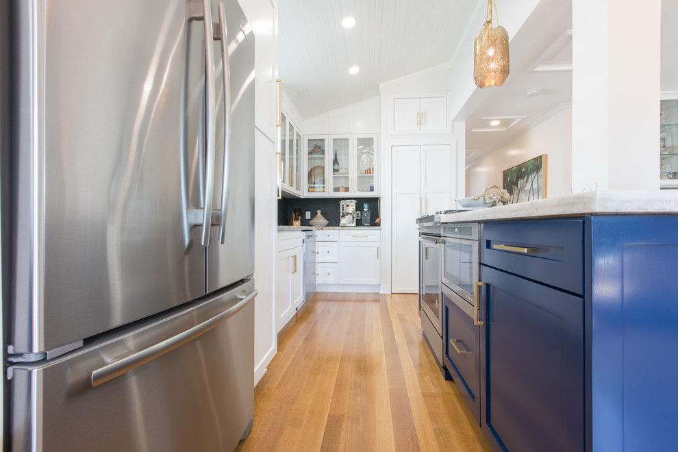 Photo of a small coastal galley kitchen/diner in Miami with blue cabinets, marble worktops, stainless steel appliances, medium hardwood flooring and no island.