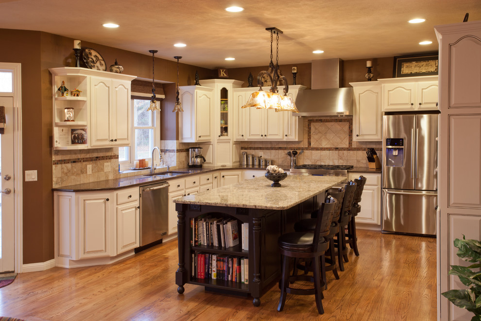 Example of a large classic u-shaped light wood floor eat-in kitchen design in St Louis with an undermount sink, recessed-panel cabinets, white cabinets, granite countertops, beige backsplash, ceramic backsplash, stainless steel appliances and an island