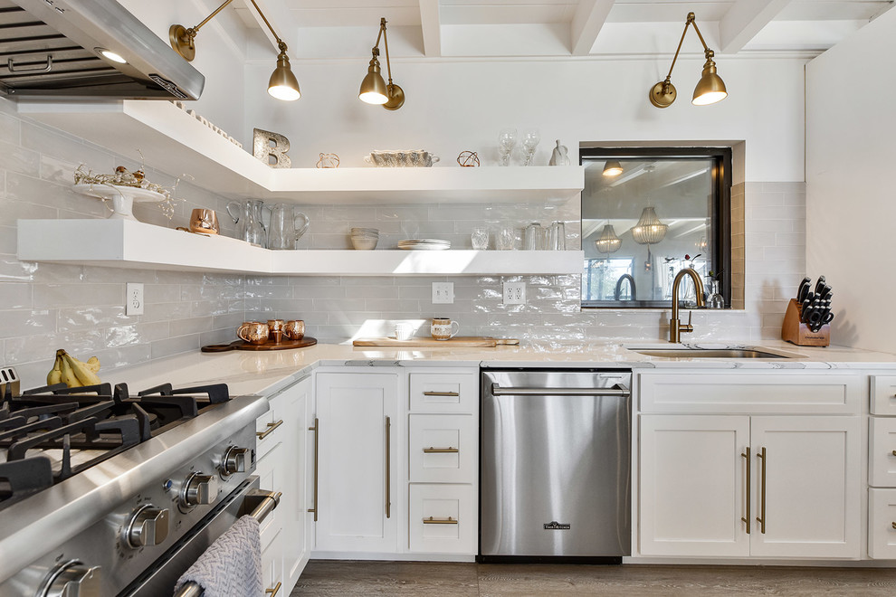 Inspiration for a farmhouse l-shaped gray floor and light wood floor kitchen remodel in Jacksonville with a single-bowl sink, shaker cabinets, quartz countertops, gray backsplash, stainless steel appliances, white cabinets and subway tile backsplash