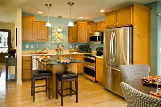 Klassische Wohnküche in L-Form mit Einbauwaschbecken, Schrankfronten mit vertiefter Füllung, hellen Holzschränken, Granit-Arbeitsplatte, Küchenrückwand in Blau und Küchengeräten aus Edelstahl in Sonstige