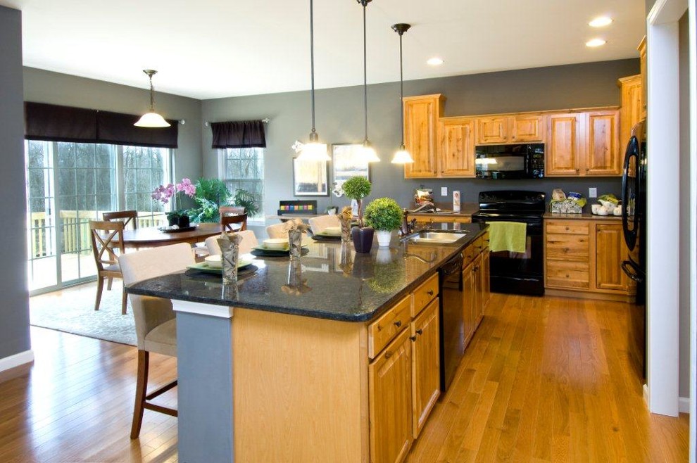 Foto di una cucina chic con lavello da incasso, ante in stile shaker, ante in legno chiaro, top in granito, paraspruzzi grigio e elettrodomestici neri