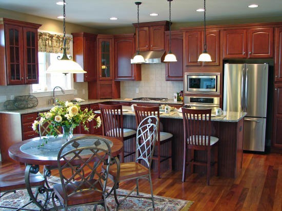 Eat-in kitchen - traditional l-shaped eat-in kitchen idea in Other with a drop-in sink, recessed-panel cabinets, dark wood cabinets, granite countertops, beige backsplash, stone tile backsplash and stainless steel appliances