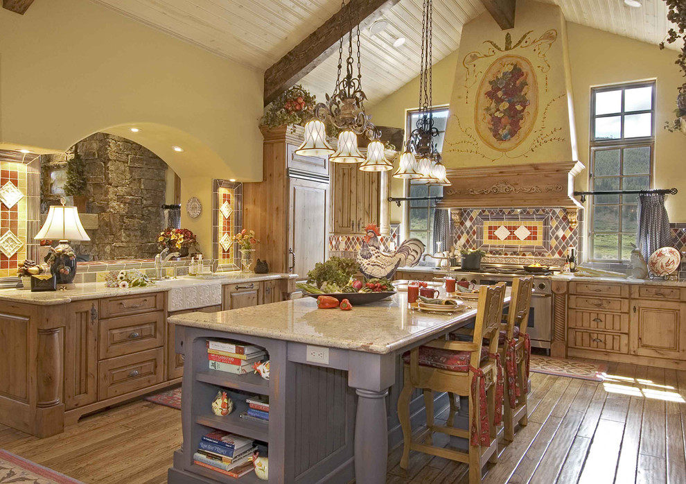 Klassisk inredning av ett avskilt, stort u-kök, med en rustik diskho, luckor med upphöjd panel, skåp i mellenmörkt trä, granitbänkskiva, flerfärgad stänkskydd, stänkskydd i stenkakel, integrerade vitvaror, ljust trägolv och en köksö