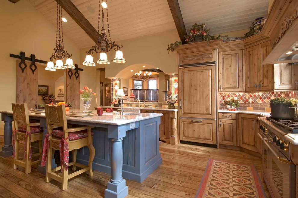 Example of a large mountain style u-shaped light wood floor enclosed kitchen design in Denver with raised-panel cabinets, medium tone wood cabinets, multicolored backsplash, paneled appliances, a farmhouse sink, granite countertops, stone tile backsplash and an island