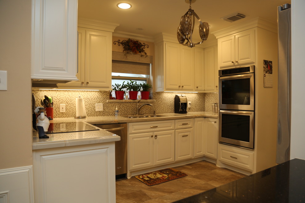 Foto på ett litet vintage kök, med en dubbel diskho, luckor med upphöjd panel, vita skåp, beige stänkskydd, stänkskydd i glaskakel, rostfria vitvaror, klinkergolv i keramik och brunt golv