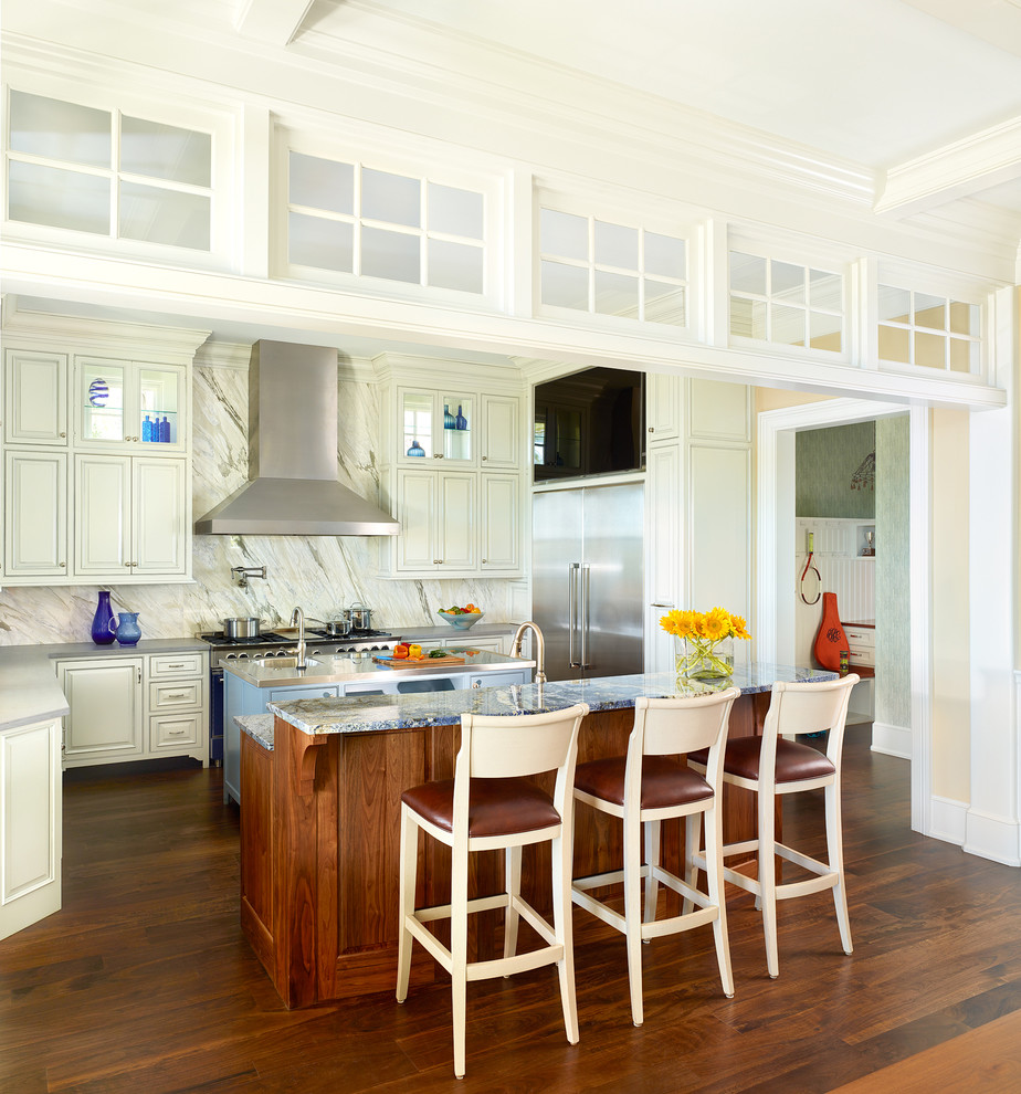 Cette photo montre une cuisine américaine chic avec des portes de placard blanches, une crédence blanche, parquet foncé et 2 îlots.