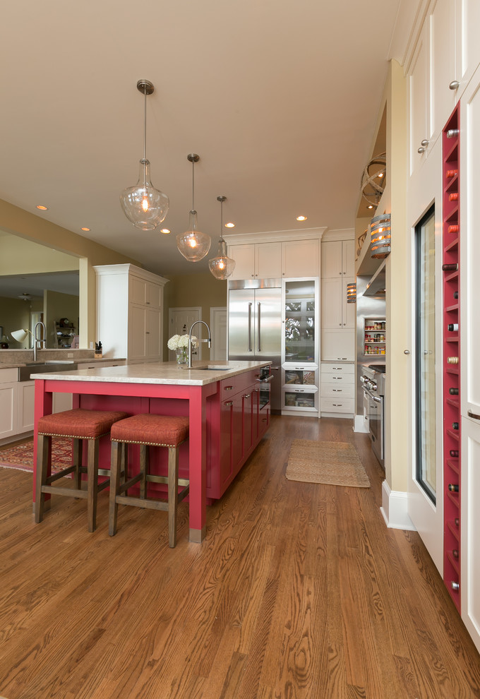 Cette photo montre une cuisine américaine parallèle chic avec un placard à porte shaker, des portes de placard rouges, un plan de travail en granite, un électroménager en acier inoxydable, un sol en bois brun et îlot.
