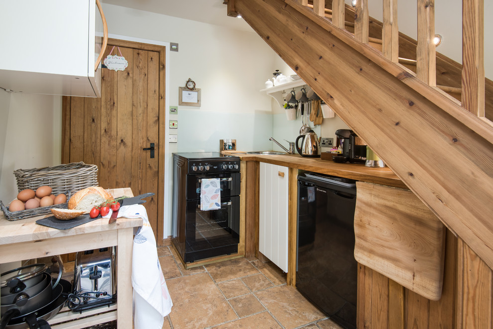 Immagine di una piccola cucina a L stile rurale chiusa con top in legno, paraspruzzi blu, elettrodomestici neri, pavimento in terracotta, pavimento arancione, ante a filo e paraspruzzi con piastrelle di vetro