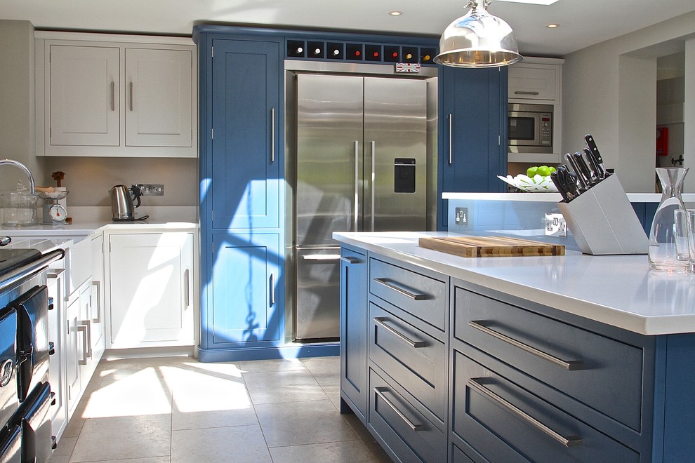 Photo of a farmhouse kitchen in Berkshire with shaker cabinets, blue cabinets, stainless steel appliances and an island.