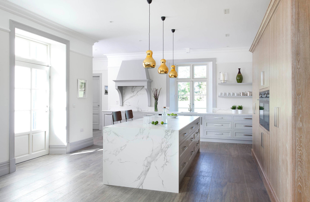 Exempel på ett stort modernt kök, med en undermonterad diskho, luckor med upphöjd panel, grå skåp, bänkskiva i kvarts, vitt stänkskydd, stänkskydd i sten, svarta vitvaror, klinkergolv i porslin, en köksö och brunt golv