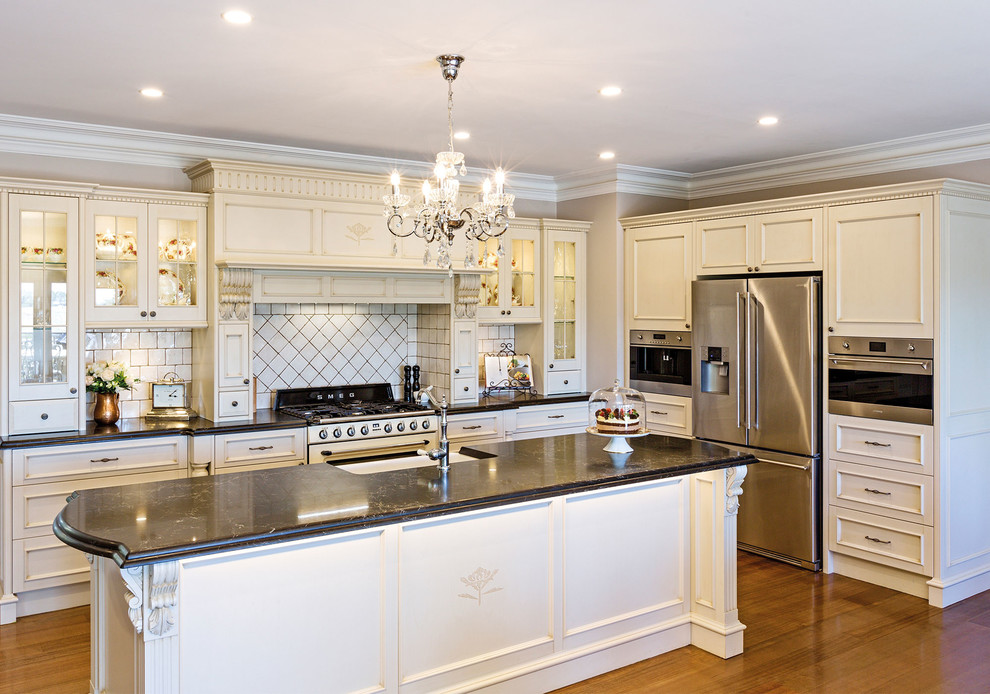 Example of a mid-sized u-shaped medium tone wood floor and brown floor eat-in kitchen design in Other with shaker cabinets, yellow cabinets, an island, a farmhouse sink, terrazzo countertops, white backsplash, subway tile backsplash, white appliances and white countertops