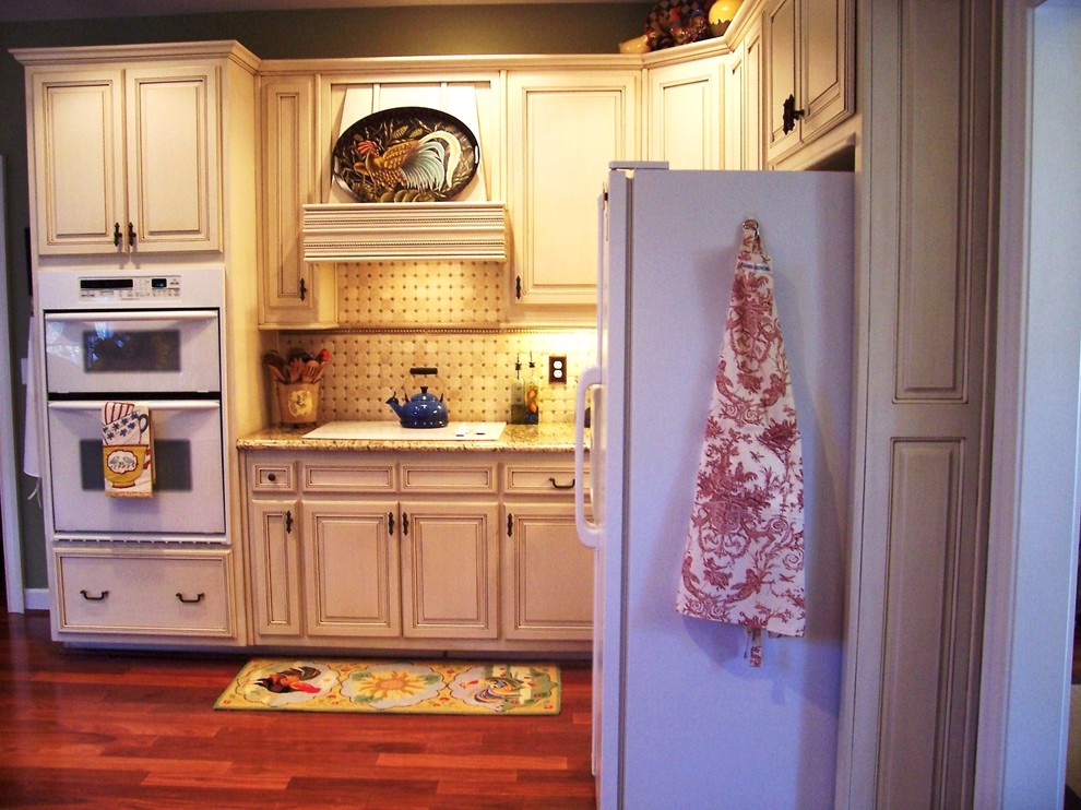 Modelo de cocinas en L clásica con armarios con paneles con relieve, puertas de armario beige y electrodomésticos blancos