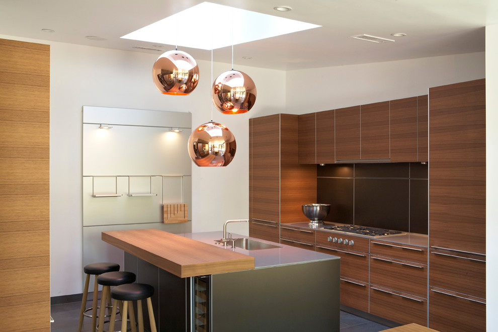 Moderne Küche mit Waschbecken, flächenbündigen Schrankfronten, hellbraunen Holzschränken, Küchenrückwand in Schwarz und Elektrogeräten mit Frontblende in Los Angeles