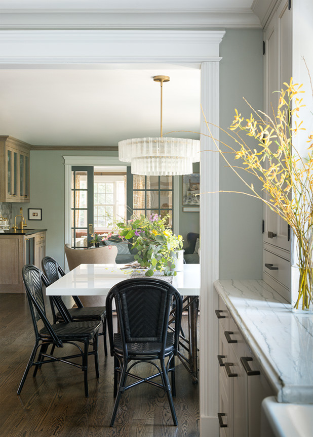 Bild på ett stort vintage vit vitt kök och matrum, med en nedsänkt diskho, bänkskiva i kvartsit, grått stänkskydd, stänkskydd i stenkakel, luckor med profilerade fronter, vita skåp, mellanmörkt trägolv och brunt golv