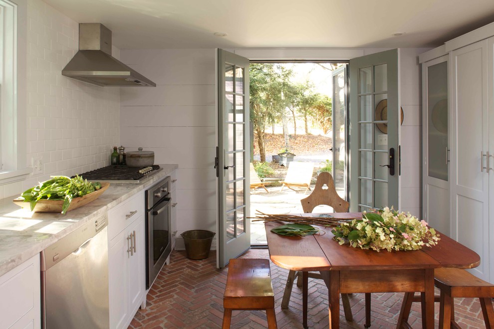 Kitchen - farmhouse brick floor kitchen idea in New York with shaker cabinets, white cabinets, marble countertops, white backsplash, subway tile backsplash and stainless steel appliances