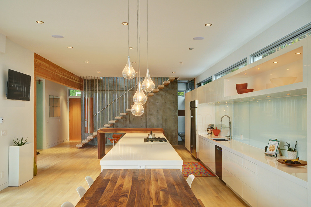 Zweizeilige, Geräumige Moderne Wohnküche mit Unterbauwaschbecken, flächenbündigen Schrankfronten, weißen Schränken, Küchengeräten aus Edelstahl und Kücheninsel in Vancouver
