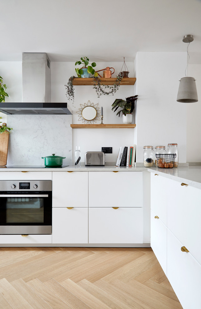 Foto på ett mellanstort nordiskt grå kök, med en nedsänkt diskho, släta luckor, vita skåp, bänkskiva i kvartsit, stänkskydd i sten, rostfria vitvaror, ljust trägolv och en halv köksö