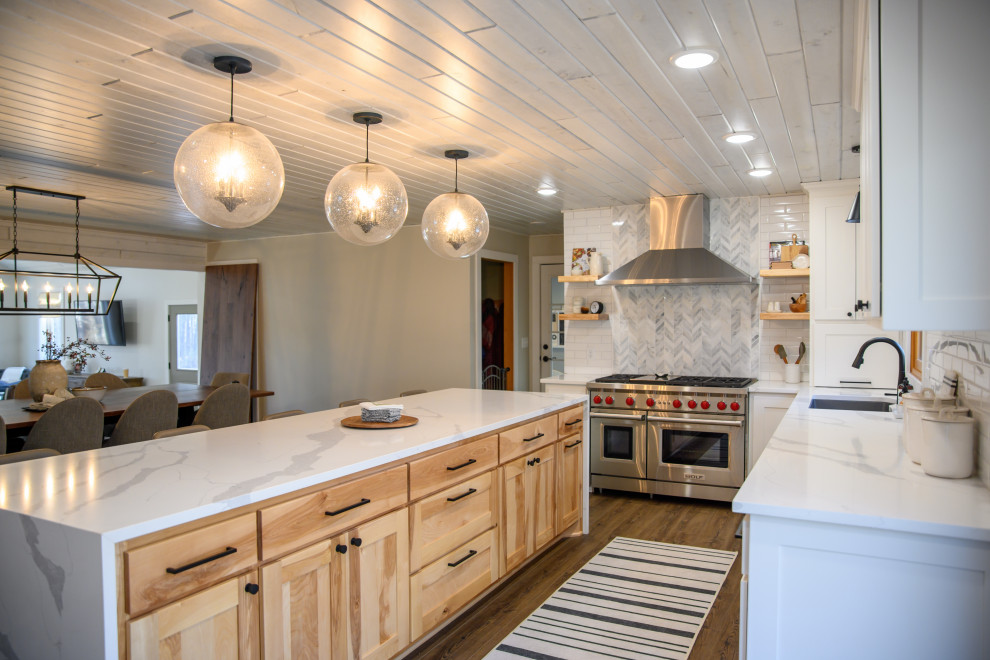 Open concept kitchen - large transitional l-shaped medium tone wood floor and brown floor open concept kitchen idea in Minneapolis with an undermount sink, shaker cabinets, white cabinets, white backsplash, subway tile backsplash, stainless steel appliances, an island and white countertops