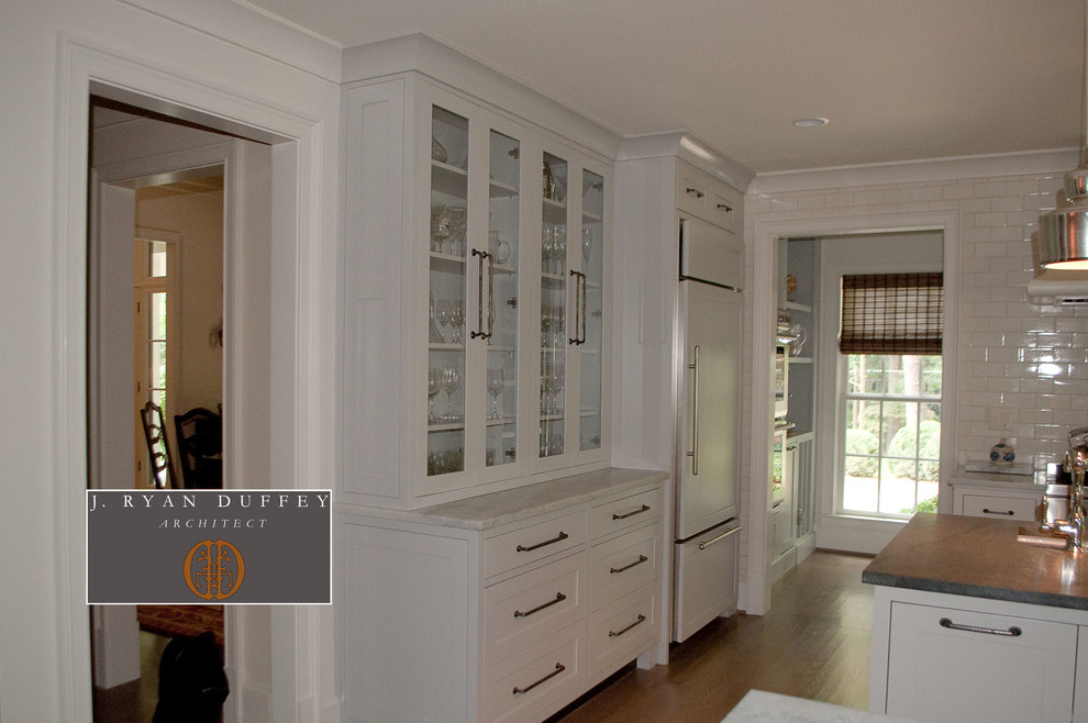 Ejemplo de cocina tradicional renovada con armarios estilo shaker, puertas de armario blancas, salpicadero blanco, salpicadero de azulejos tipo metro y electrodomésticos con paneles