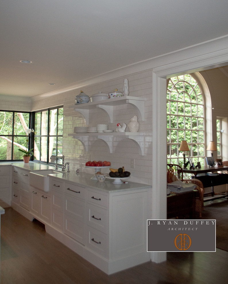 Photo of a traditional u-shaped kitchen/diner in Atlanta with shaker cabinets, white cabinets, white splashback, metro tiled splashback and integrated appliances.