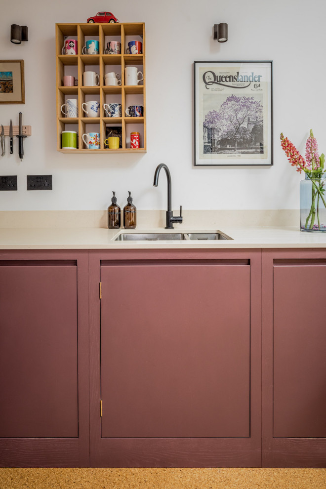 Small trendy u-shaped cork floor eat-in kitchen photo in West Midlands with a drop-in sink, flat-panel cabinets, purple cabinets, quartz countertops and black appliances