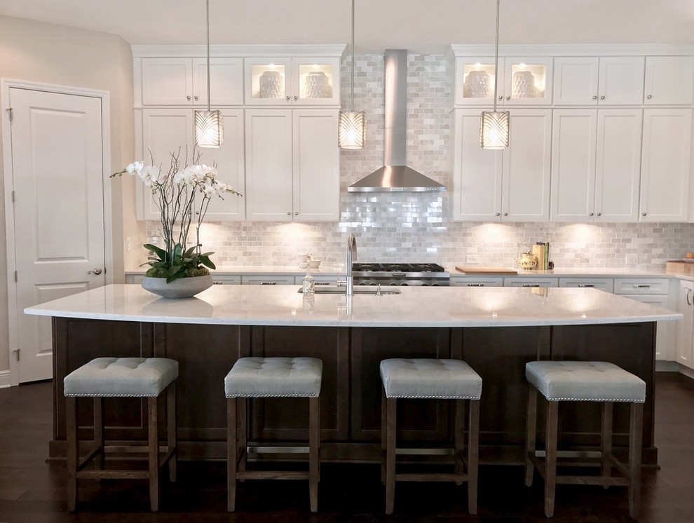 Exempel på ett stort klassiskt vit vitt l-kök, med en trippel diskho, luckor med infälld panel, vita skåp, bänkskiva i kvarts, vitt stänkskydd, stänkskydd i marmor, rostfria vitvaror, mörkt trägolv, en köksö och brunt golv