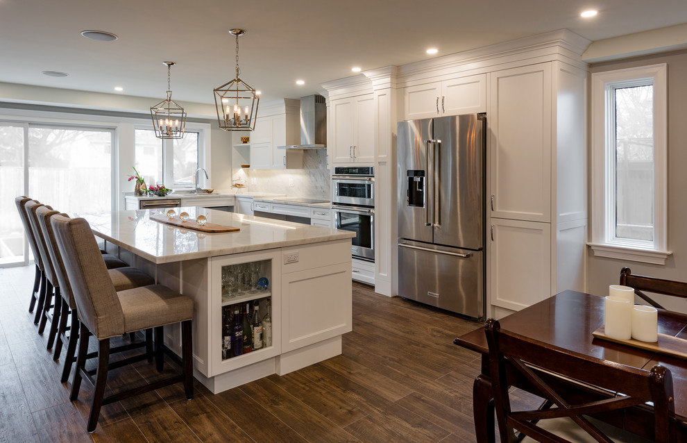 Idéer för ett mellanstort modernt vit kök, med en integrerad diskho, skåp i shakerstil, vita skåp, bänkskiva i kvartsit, vitt stänkskydd, stänkskydd i marmor, rostfria vitvaror, mellanmörkt trägolv, en köksö och brunt golv