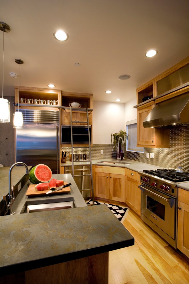 Medium sized urban l-shaped kitchen/diner in Salt Lake City with a submerged sink, shaker cabinets, medium wood cabinets, metallic splashback, stainless steel appliances, light hardwood flooring, an island and brown floors.