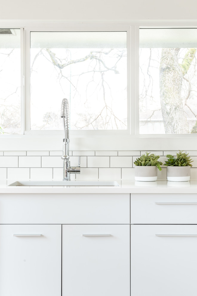 Bild på ett litet minimalistiskt flerfärgad flerfärgat kök, med en undermonterad diskho, släta luckor, vita skåp, träbänkskiva, vitt stänkskydd, stänkskydd i porslinskakel, rostfria vitvaror, mellanmörkt trägolv och brunt golv