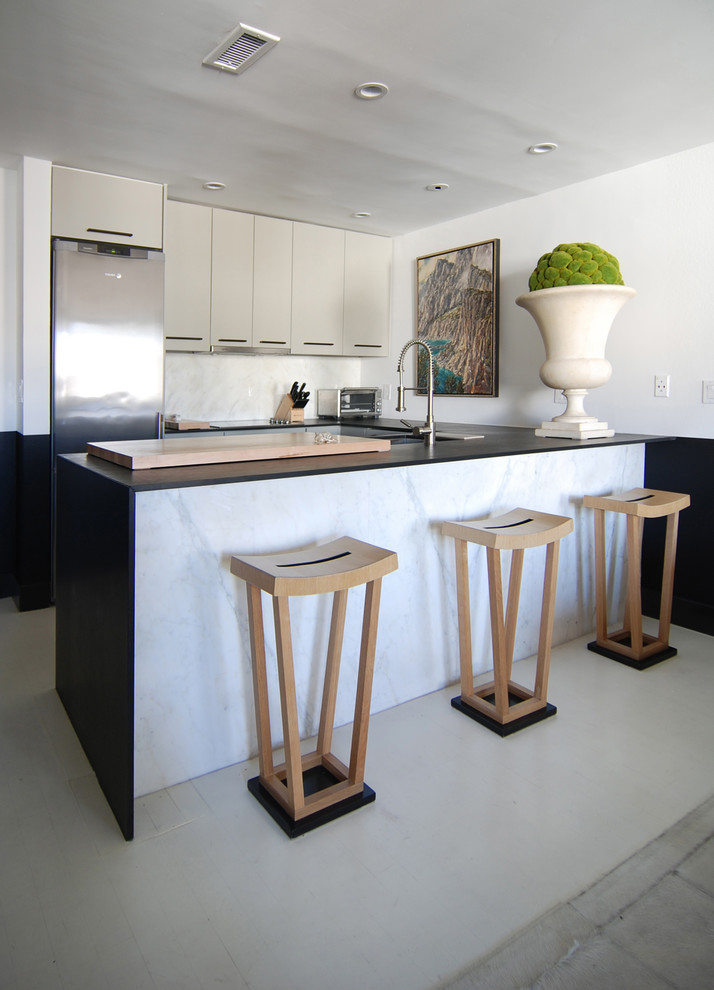 Example of a trendy u-shaped open concept kitchen design in Los Angeles with flat-panel cabinets, gray cabinets, white backsplash, stainless steel appliances, soapstone countertops, stone slab backsplash and an undermount sink