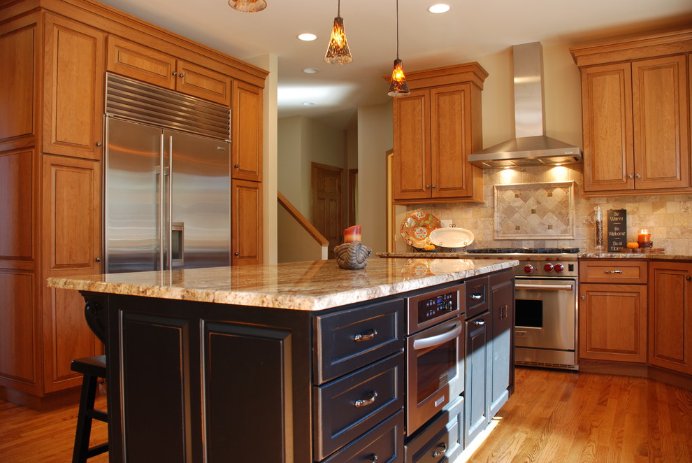 Klassische Küche mit Unterbauwaschbecken, profilierten Schrankfronten, hellbraunen Holzschränken, Granit-Arbeitsplatte, Küchengeräten aus Edelstahl und Kücheninsel in Chicago