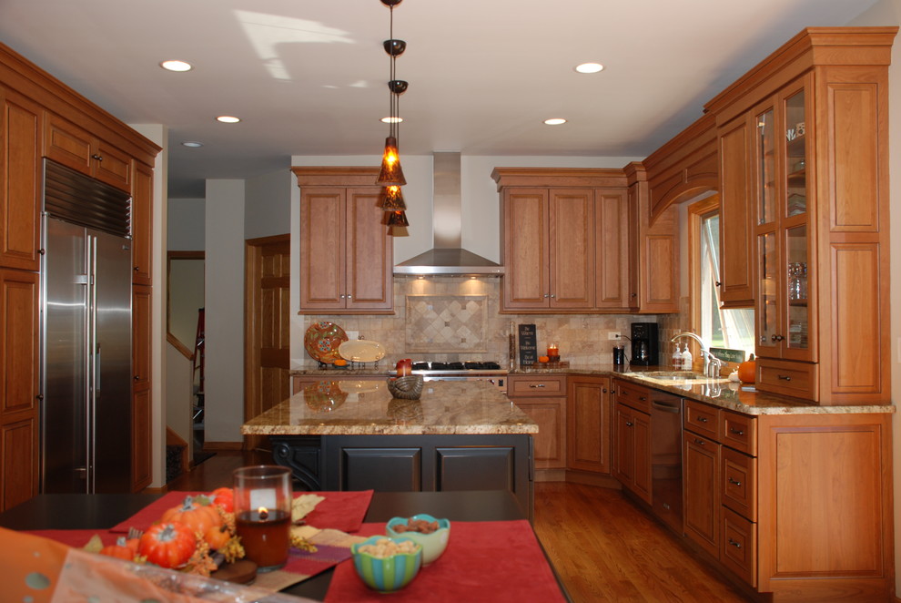 Exempel på ett klassiskt kök, med en undermonterad diskho, luckor med upphöjd panel, skåp i mellenmörkt trä, granitbänkskiva, rostfria vitvaror och en köksö