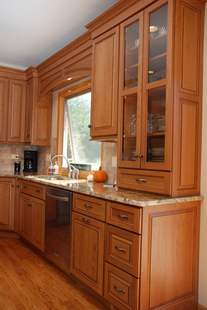 Bild på ett vintage kök, med en undermonterad diskho, luckor med upphöjd panel, skåp i mellenmörkt trä, granitbänkskiva, rostfria vitvaror och en köksö